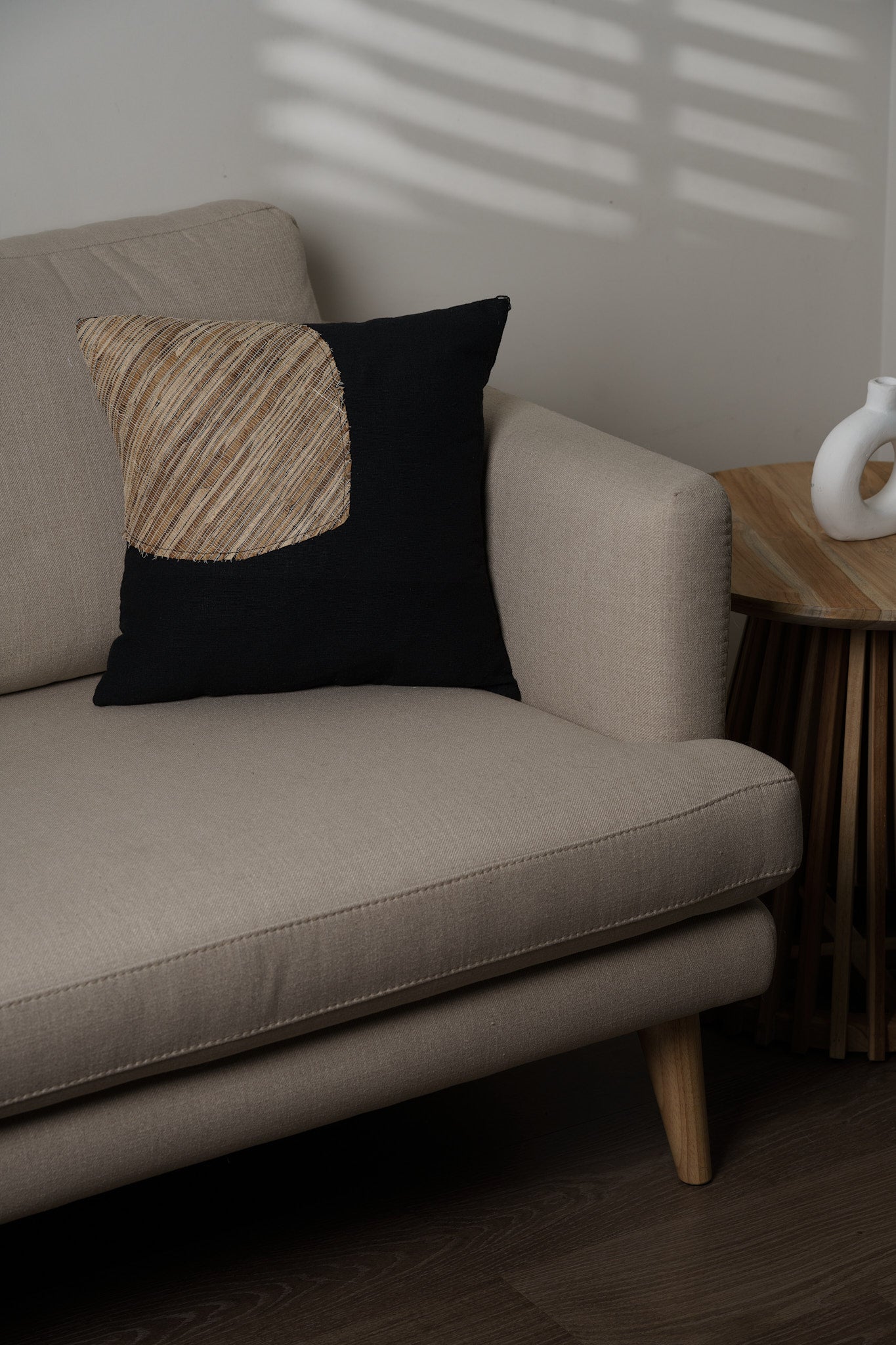 Beige sofa with a decorative pillow in a minimalistic room.